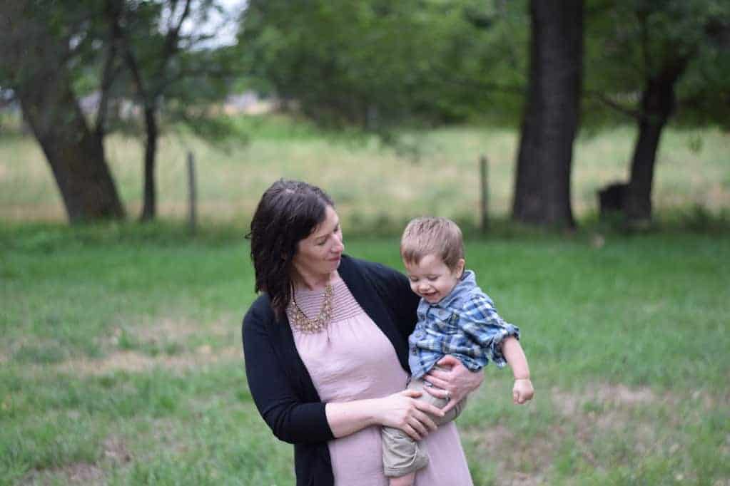 mother holding toddler son in grassy yard