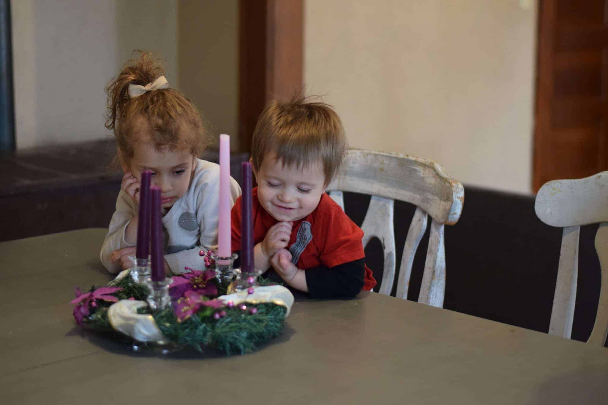 two little children sitting at a table and admiring an advent wreath