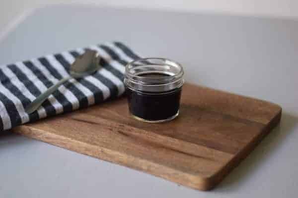 homemade elderberry syrup in a glass mason jar and resting on a rustic wood board