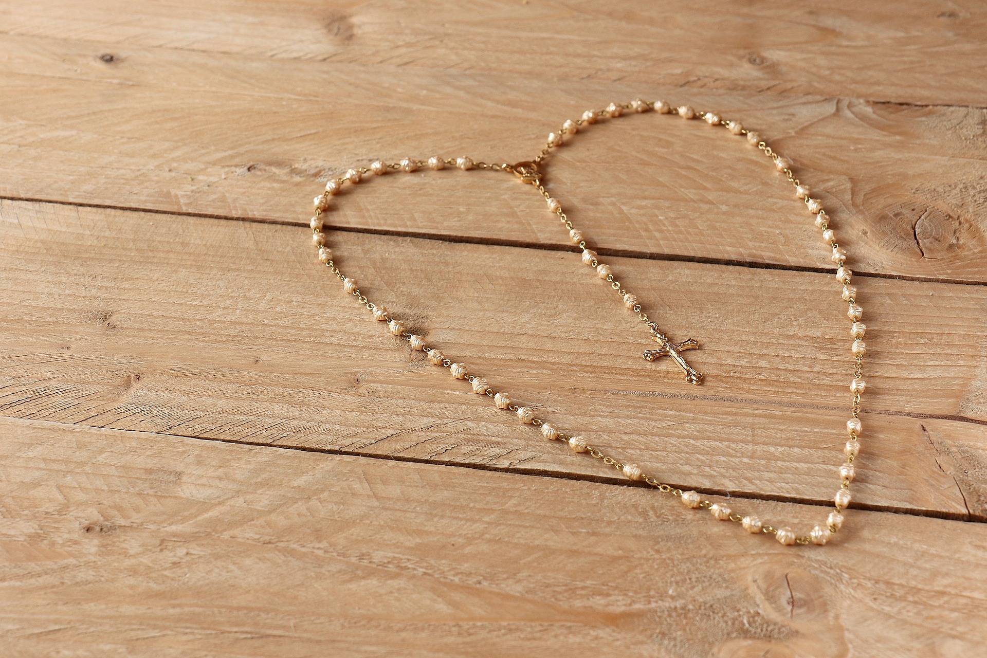 rosary in shape of a heart displayed on wooden table