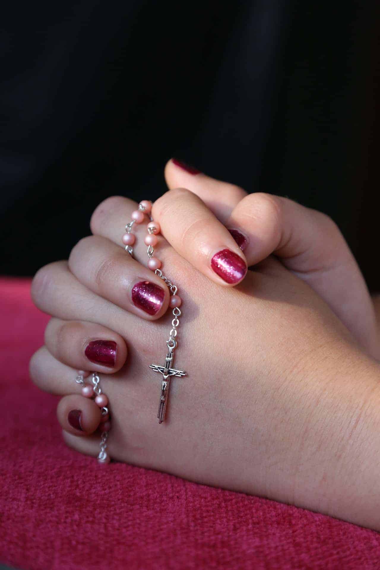 lady’s hands with pink rosary 