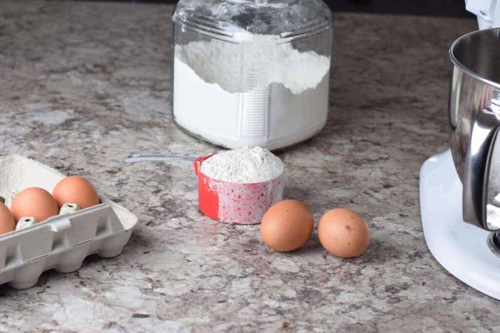 farm fresh eggs in carton, and glass storage container with flour and red measuring cup