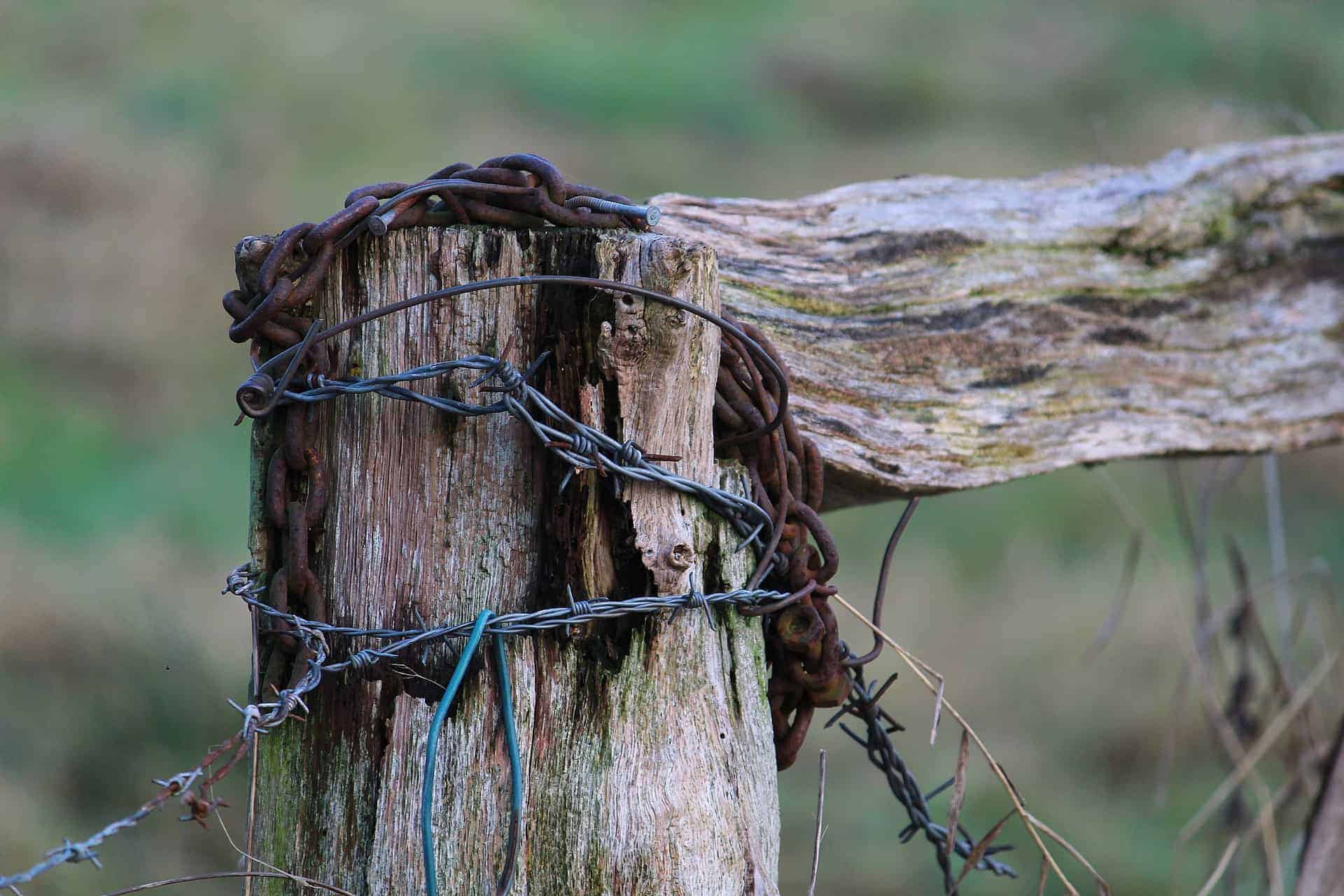 wooden fence post with barbed wire wrapped around it