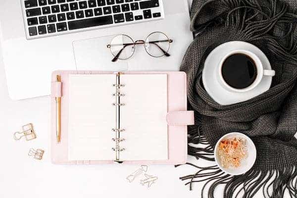 planner with a laptop, cup of coffee, and reading glasses