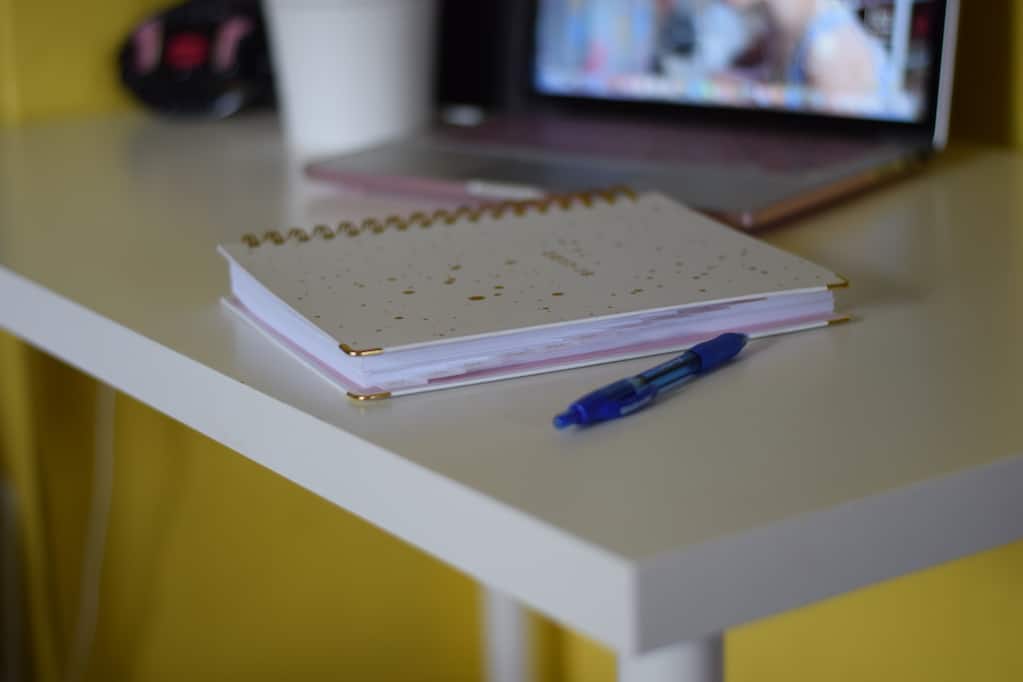 planner on desk with pen and laptop in background