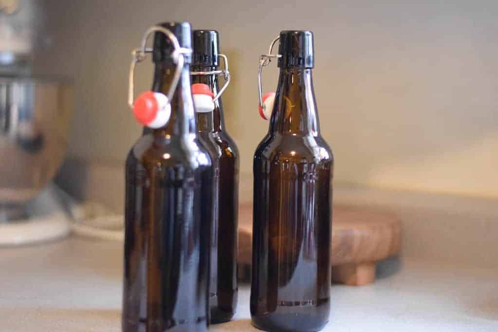 brown flip top bottles of homemade soda aka water kefir resting on the counter