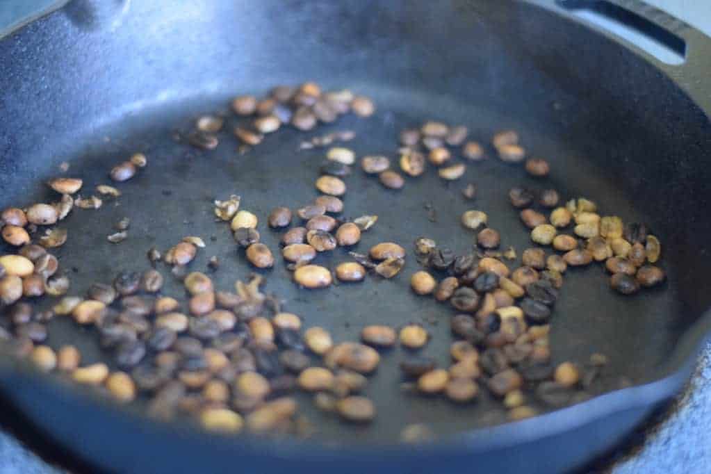 coffee beans roasting in a cast iron skillet