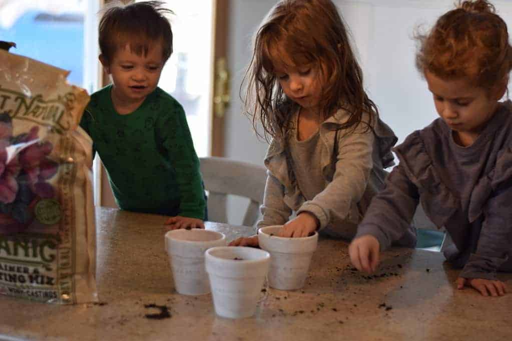 children help plant seeds in easy diy rustic herb planters