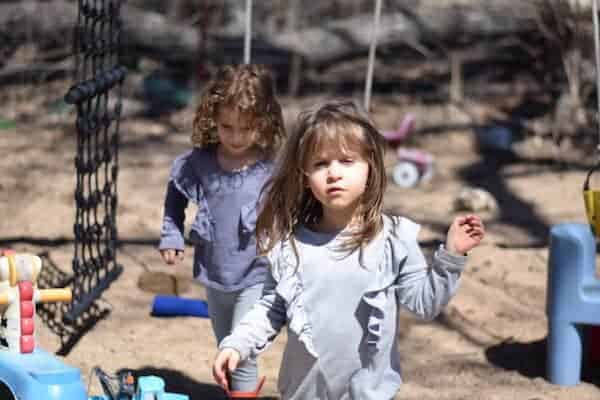 two little girls playing outside in a sand box