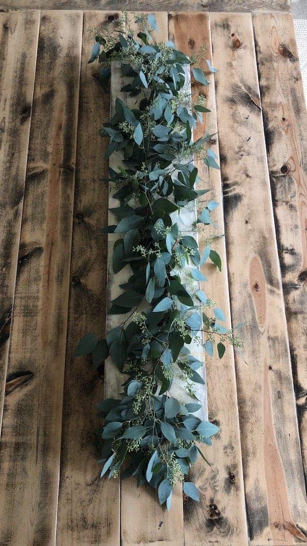 Finished eucalyptus fall tablescape on a wooden board and centered on table