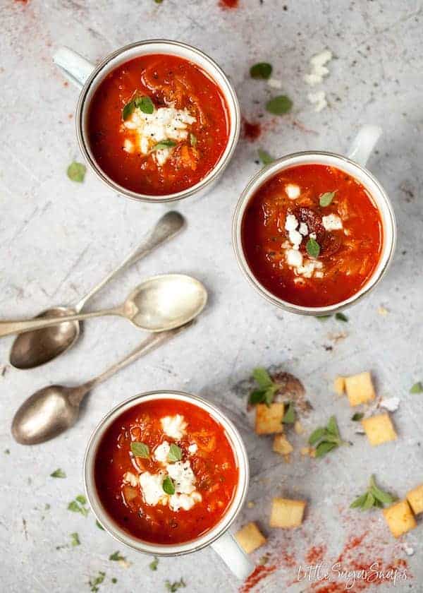 Birdseye view of 3 bowls of paprika soup on a white table