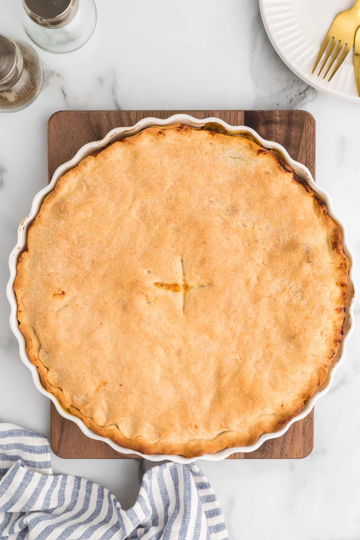 chicken pot pie baked and out of the oven on a wooden board to cool.