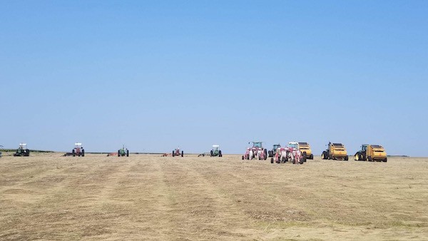 row of tractors lined up in a hay field