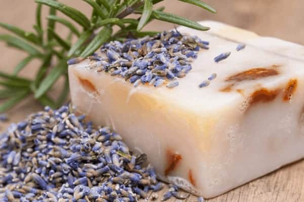 homemade bar of soap on a wood board with lavender on top