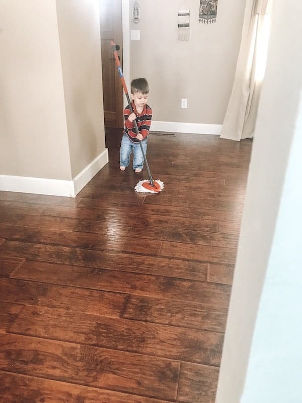 little boy using a mop on hardwood floors