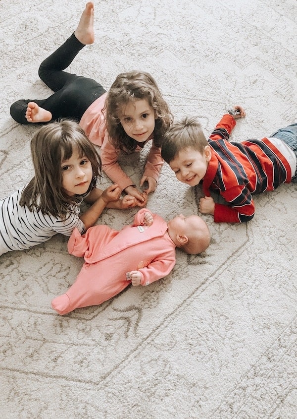 four little children laying on rug