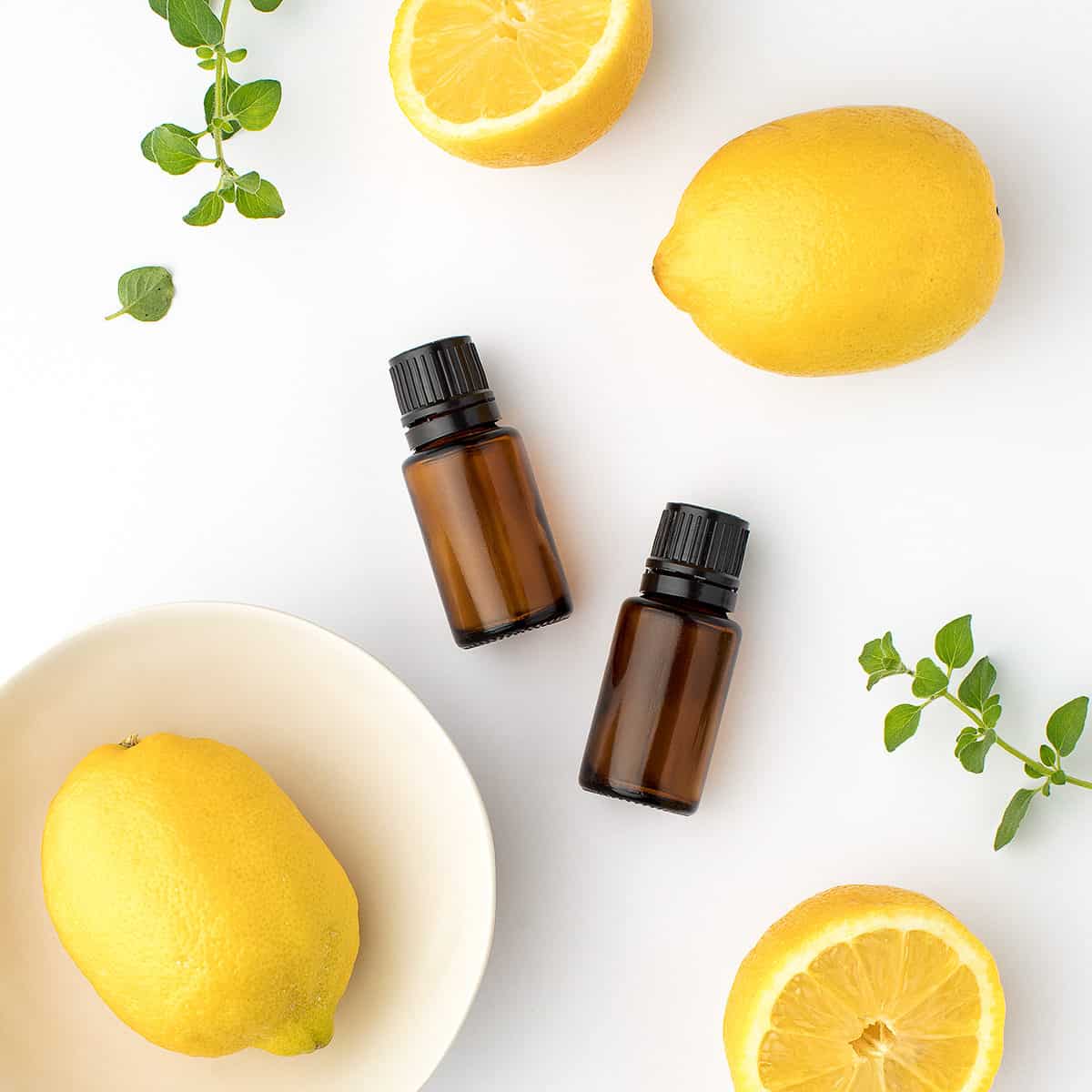 herbs and lemons on a countertop with amber colored essential oil bottles.