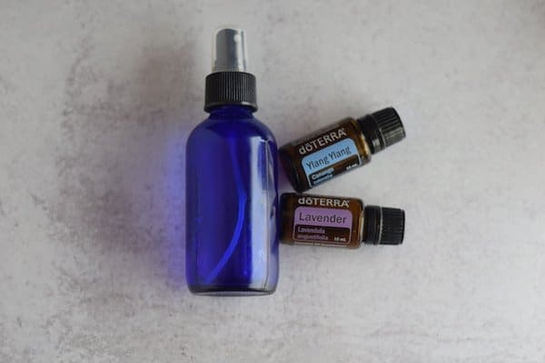 blue glass spray bottle, ylang ylang, and lavender essential oils