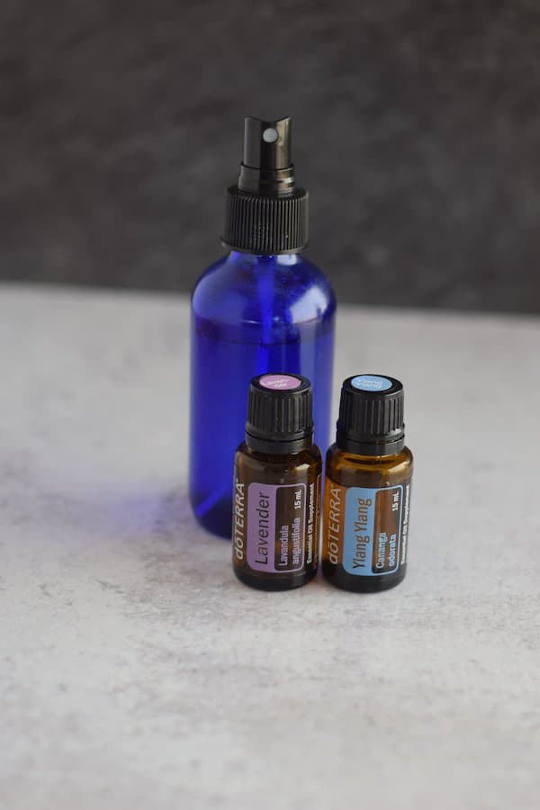 lavender, ylang ylang essential oils and blue spray bottle