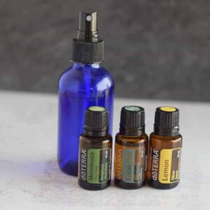 blue glass spray bottle with 3 essential oil bottles