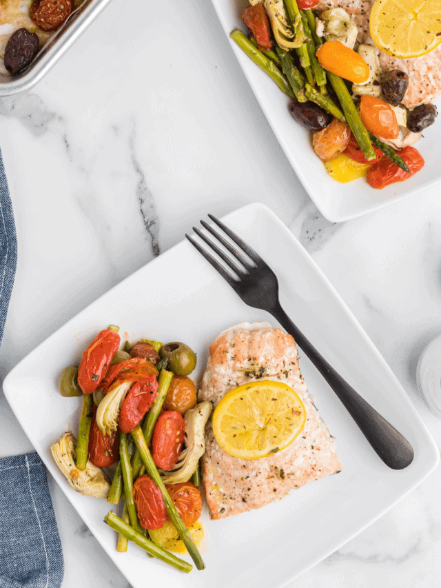 two square plates with the cooked mediterranean salmon recipe and cooked veggies