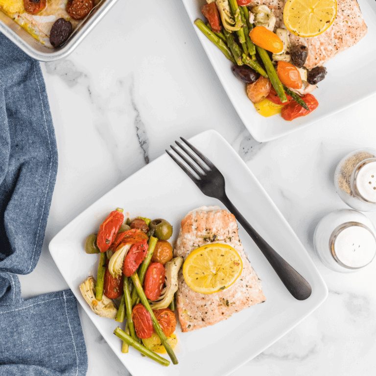 two square plates with the cooked mediterranean salmon recipe and cooked veggies