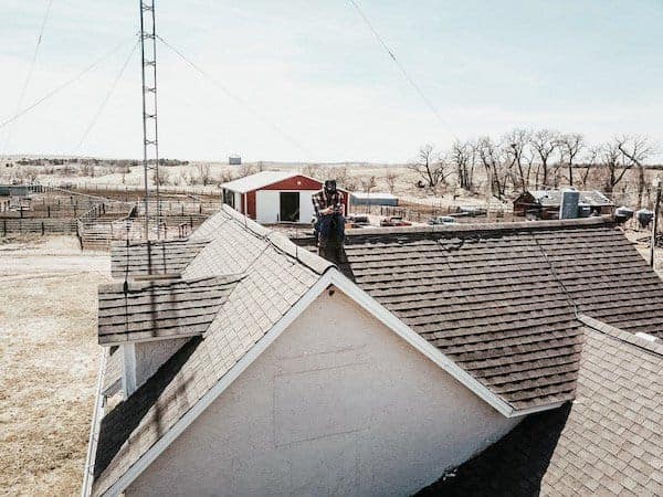 husband sitting on house roof with drone controller