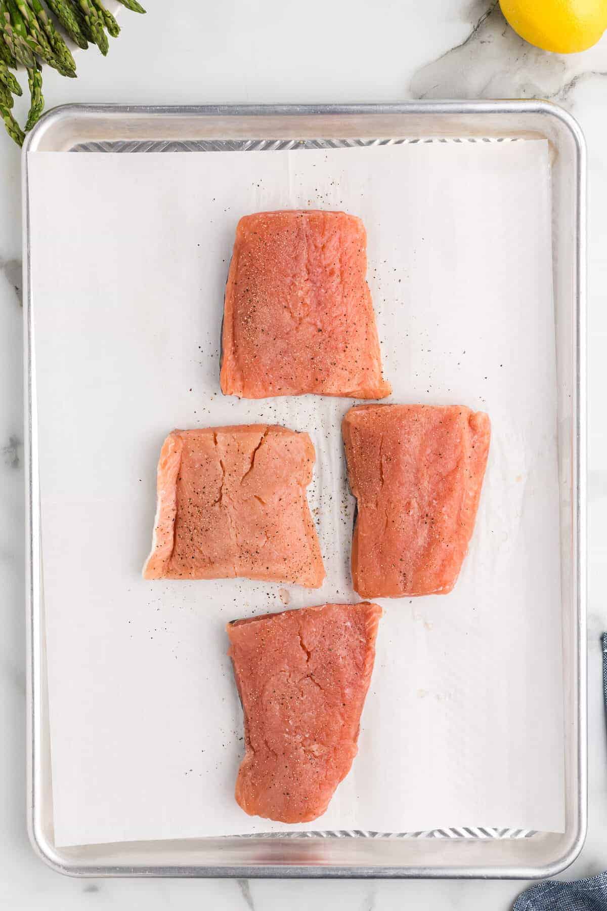 salmon on parchment paper with seasonings of salt & pepper.