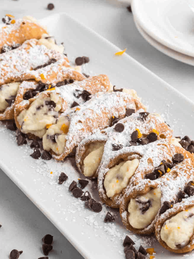 white tray with row of cannolis filled with cream and chocolate chips