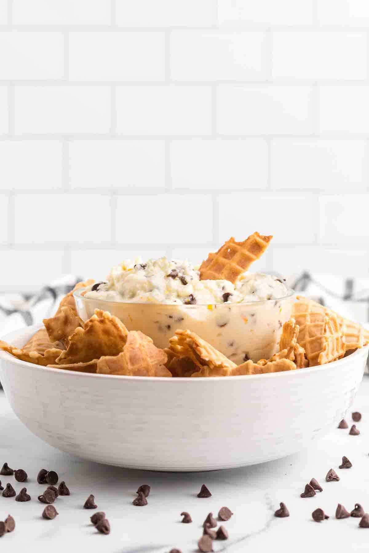 white bowl filled with the cannoli filling cream and cookies to the side. 