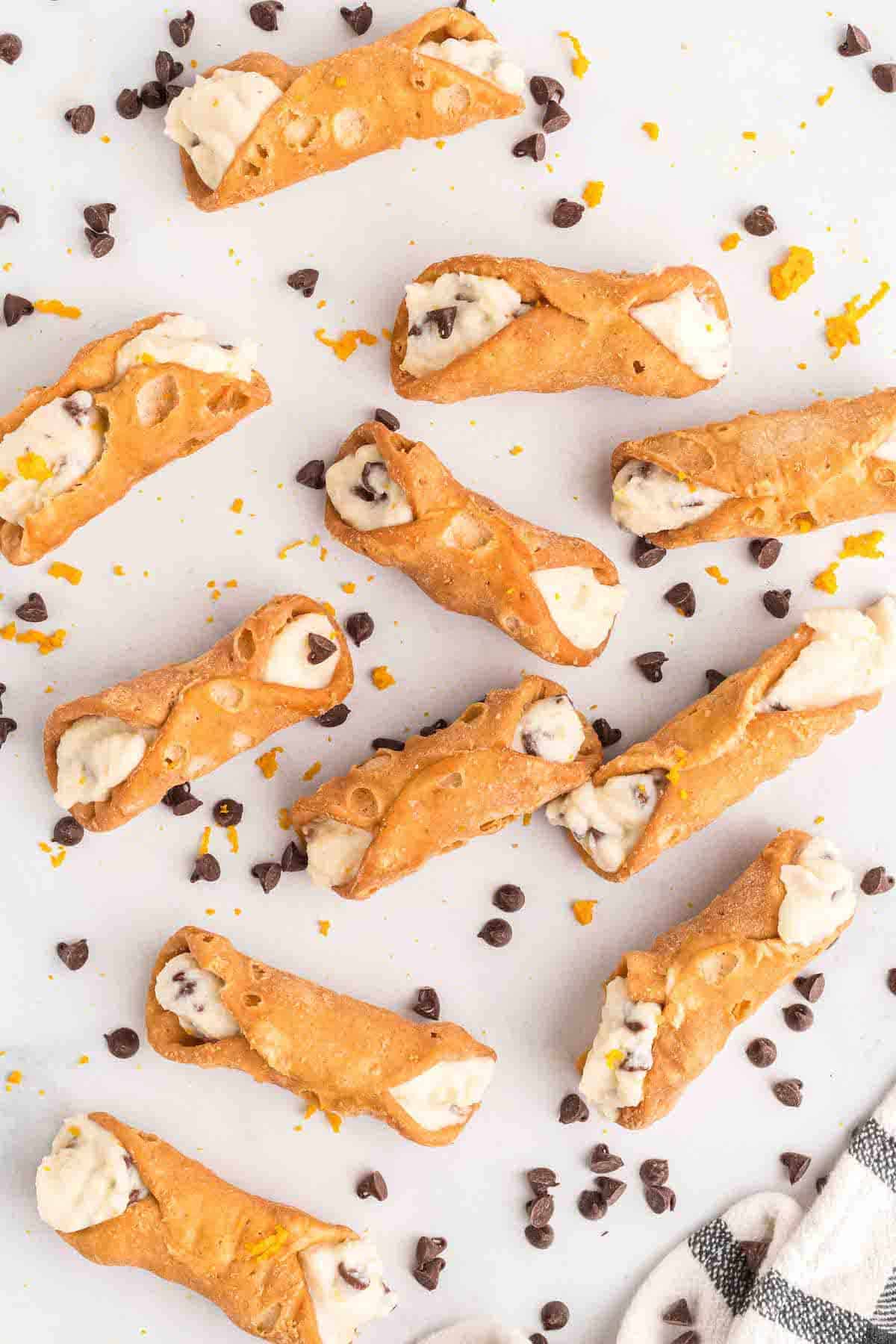 freshly filled cannoli shells with the cannoli filling recipe. Chocolate chips are scattered around the cannolis.