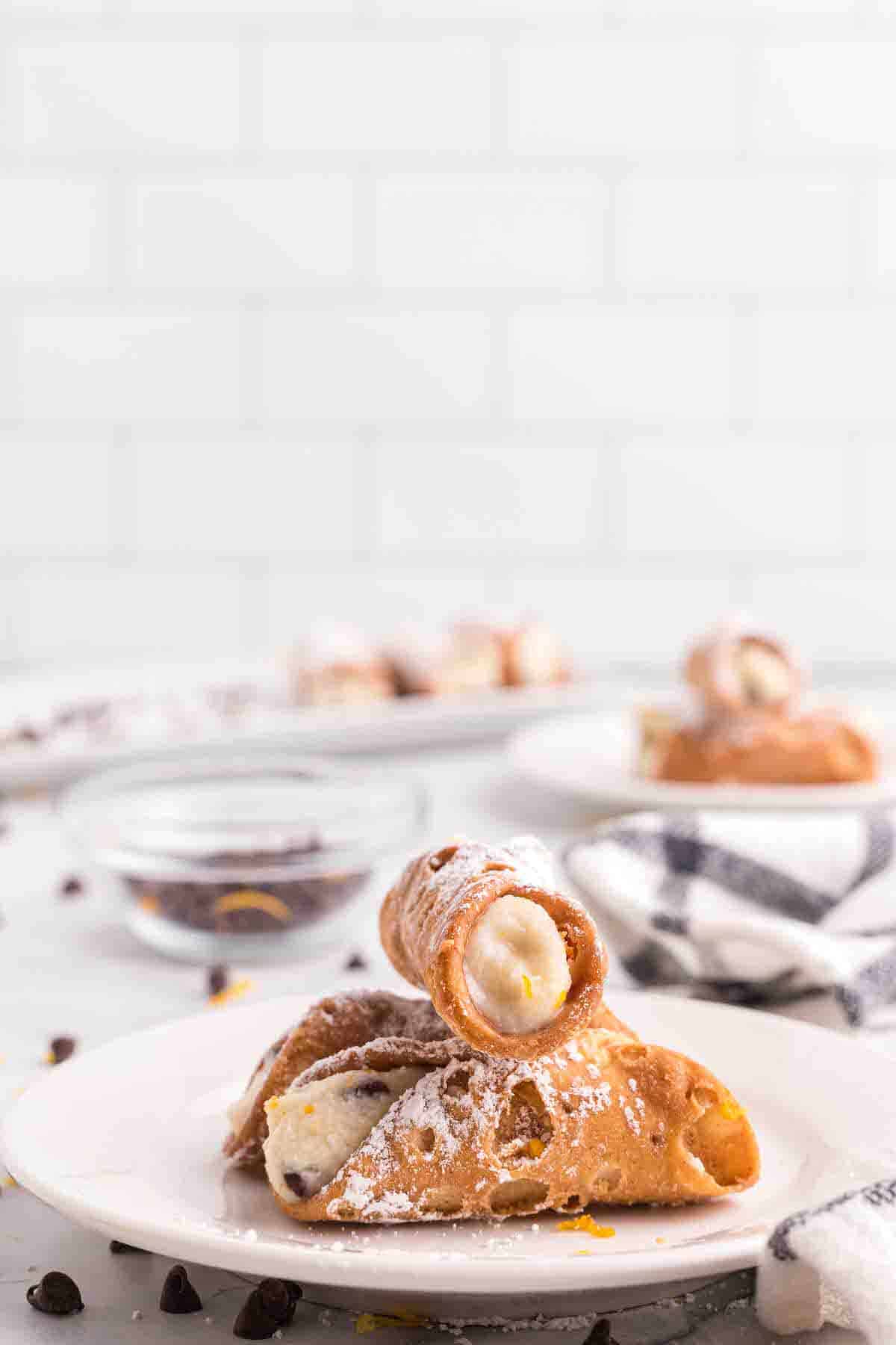 cannolis stacked on top of each other on a white plate. 