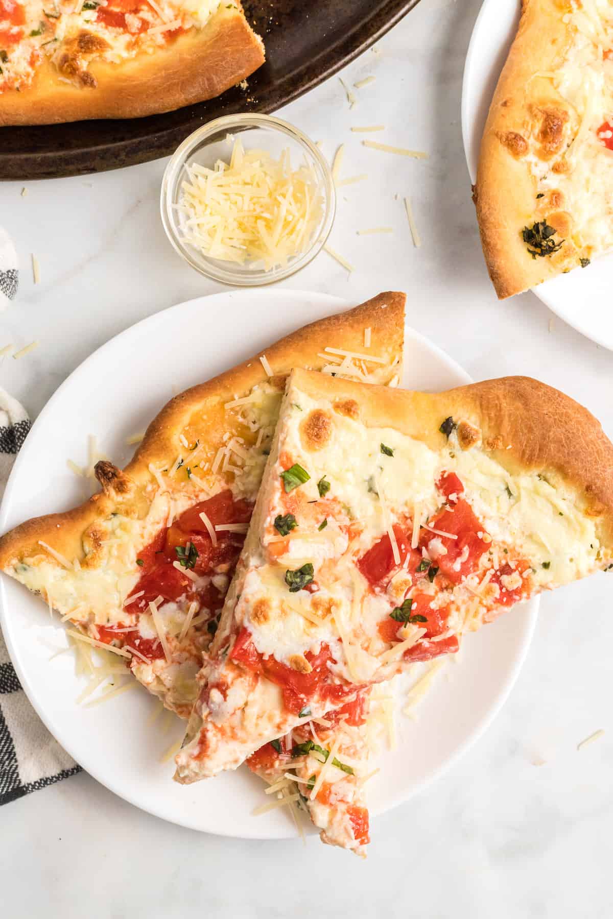 tomato basil and ricotta pizza slices on a white plate