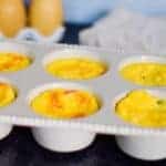 egg cup muffins in a white muffin pan with egg shakers in background