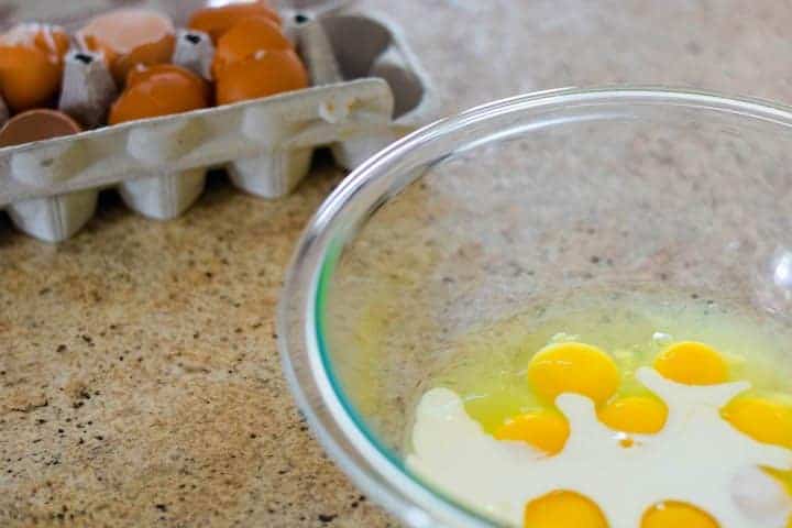 eggs in bowl with heavy cream and egg shells in background