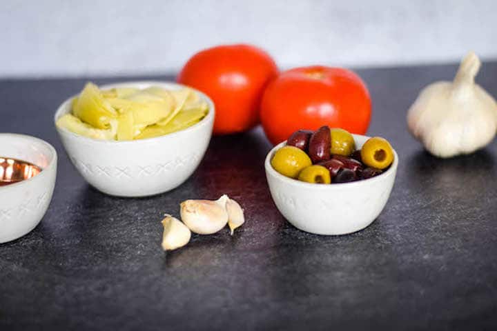 tomatoes, olives, artichokes in small white bowls
