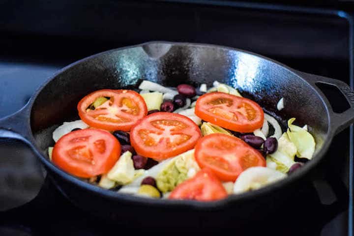 tomatoes, artichokes, olives in a cast iron skillet