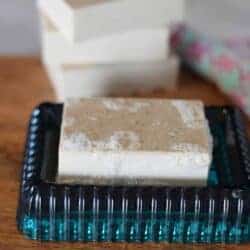 homemade bar of soap on a wood board and teal soap dish