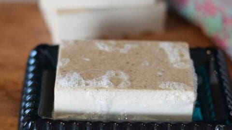 homemade bar of soap on a wood board and teal soap dish