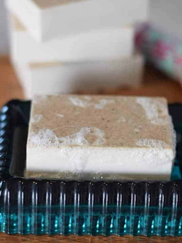 homemade bar of soap on a wood board and teal soap dish