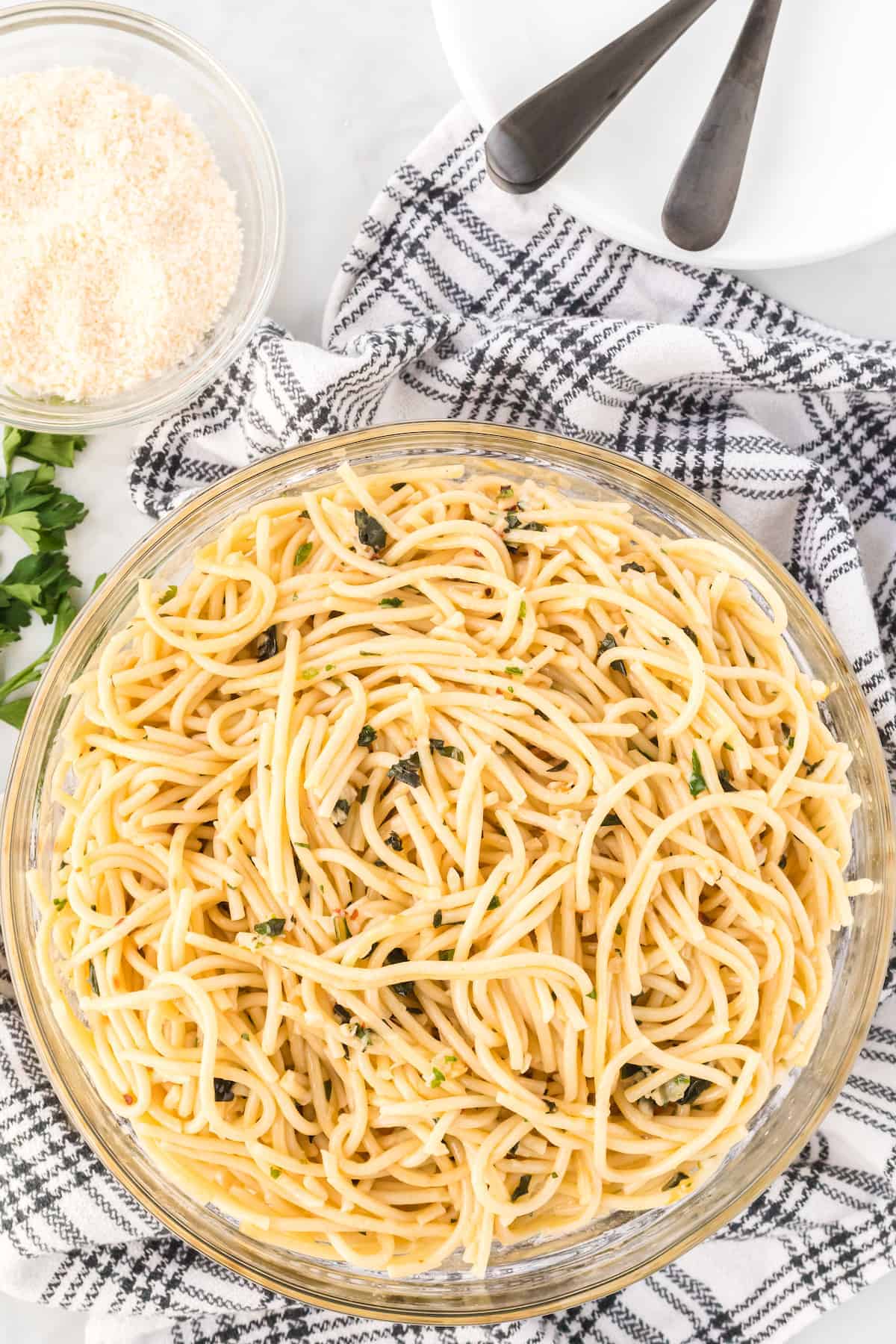 large bowl of pasta with plates and forks behind them