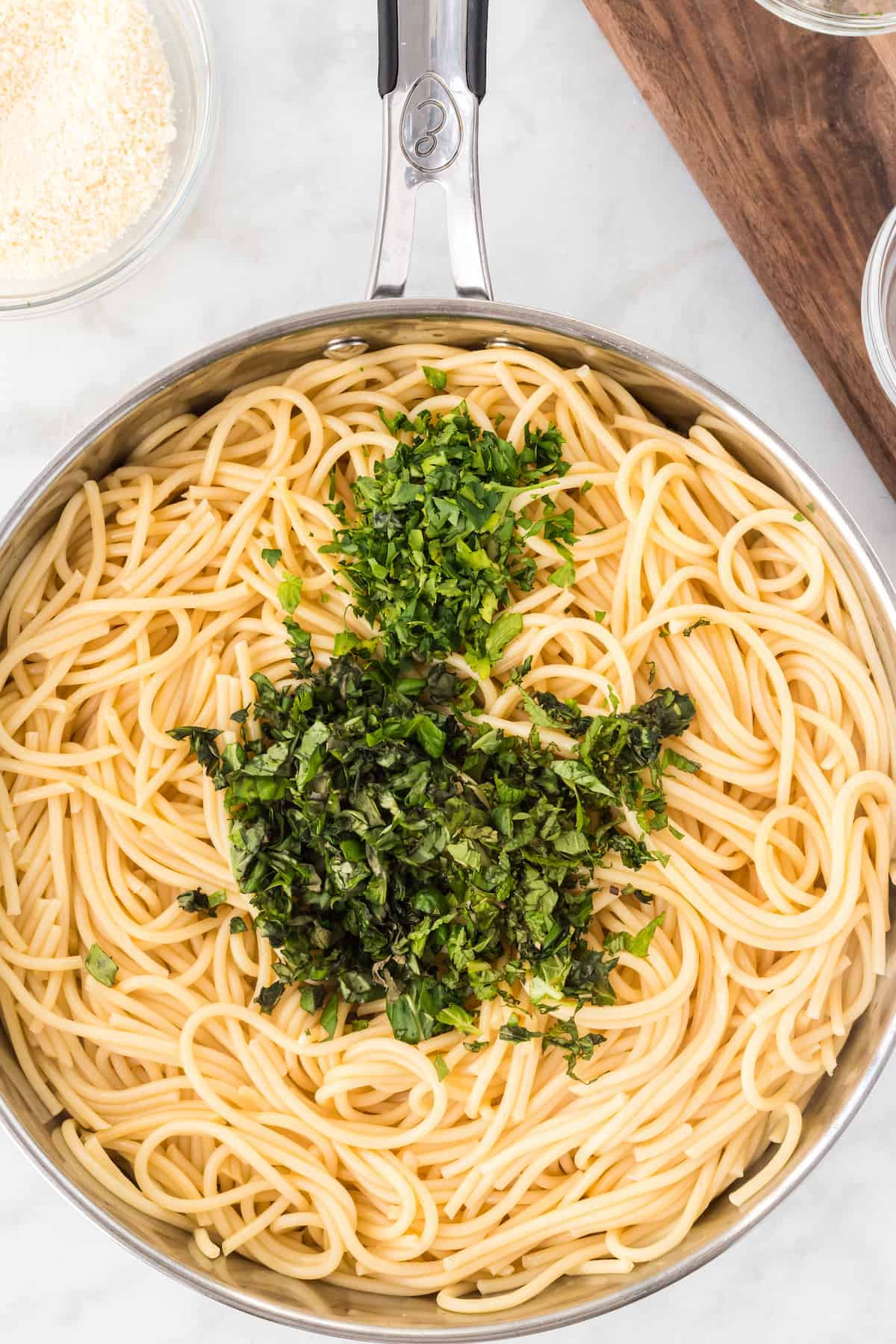 spaghetti in a large skillet with fresh herbs on top