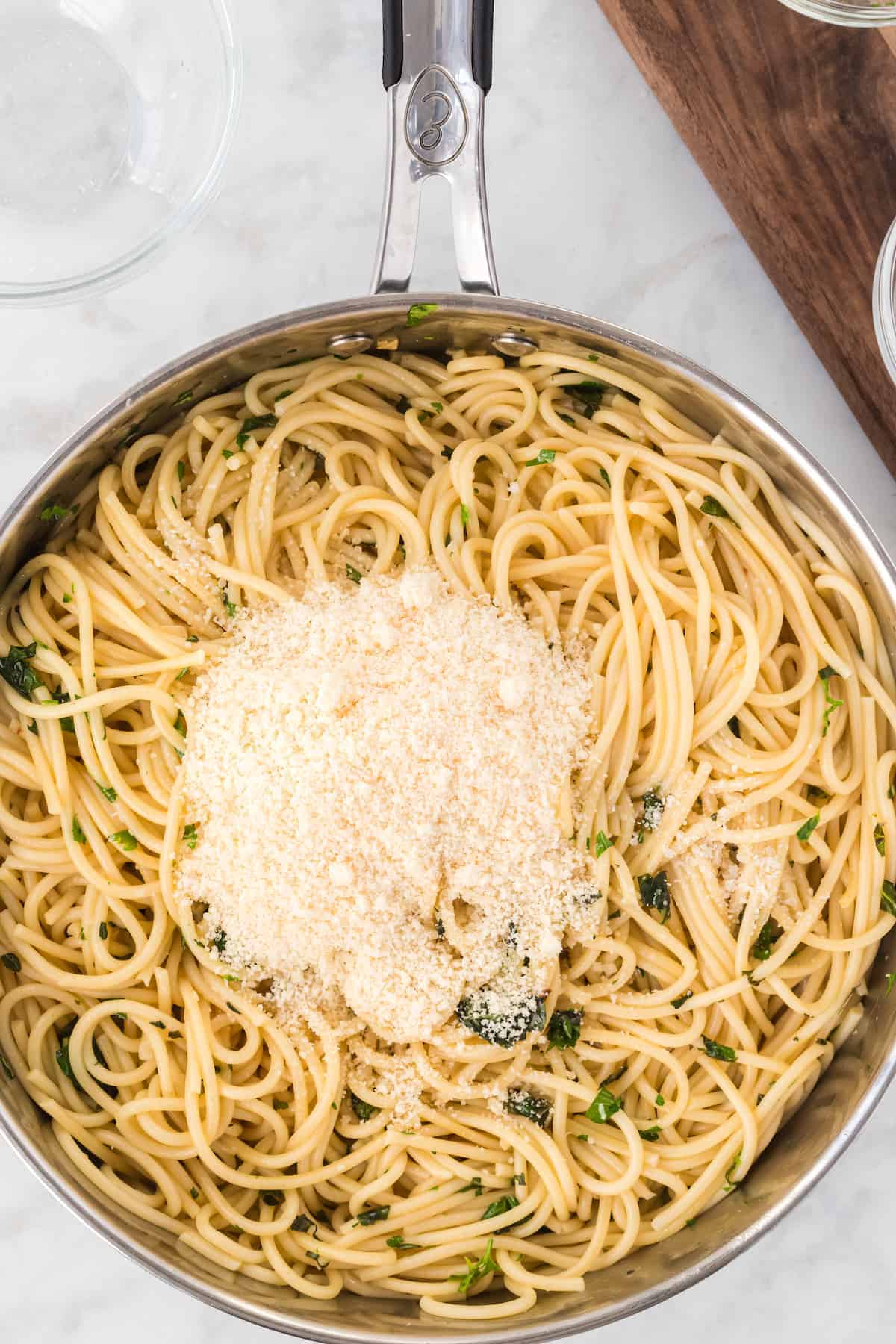 spaghetti in pan with herbs and grated cheese