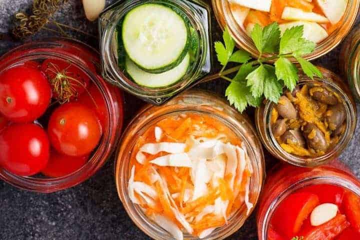 canning and preservation jars of vegetables on a black countertop