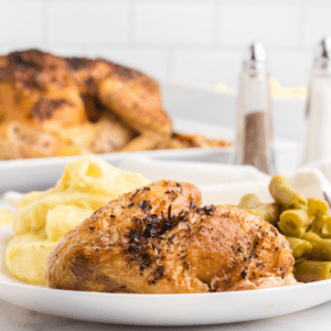 roasted chicken with Italian herbs on a white plate with mashed potatoes and green beans