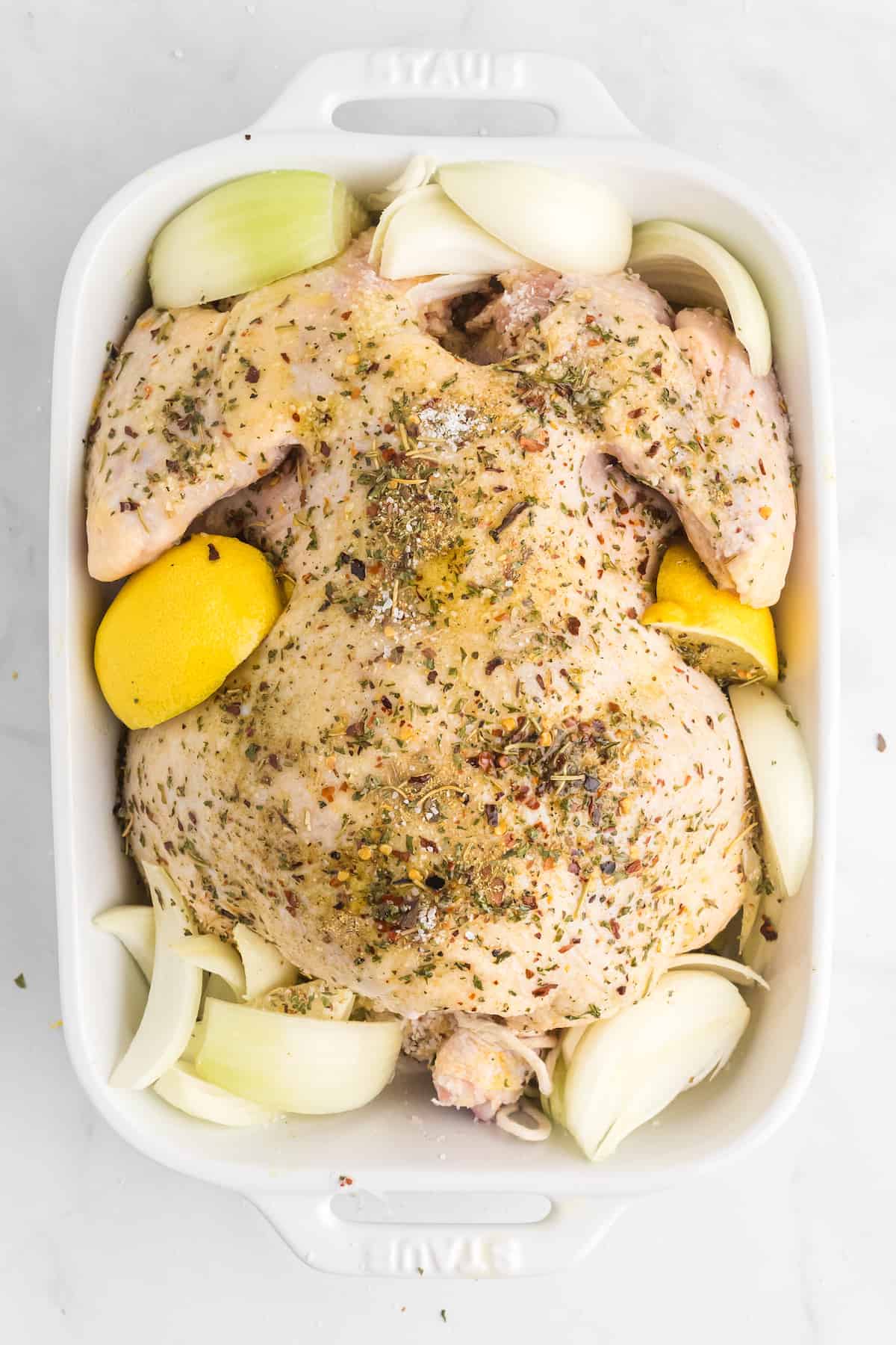italian seasoning on top of the chicken with lemons and onions to the sides
