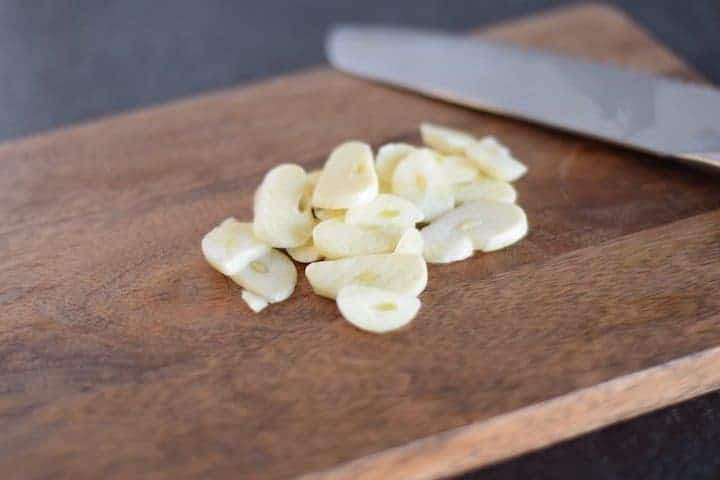 slices of garlic on a wooden cutting board