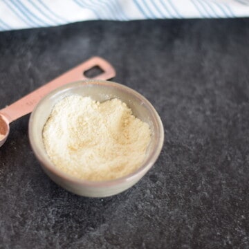 dehydrated garlic powder in a pinch bowl with copper measuring spoon