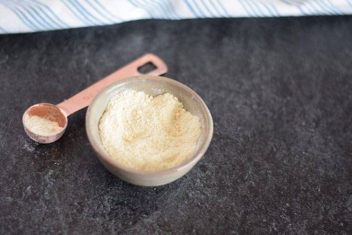 dehydrated garlic powder in a pinch bowl with copper measuring spoon