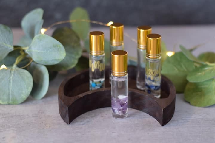 essential oil roller bottles on a decorative half moon wooden tray